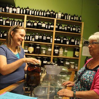 An herbalist talks to a customer at the apothecary counter